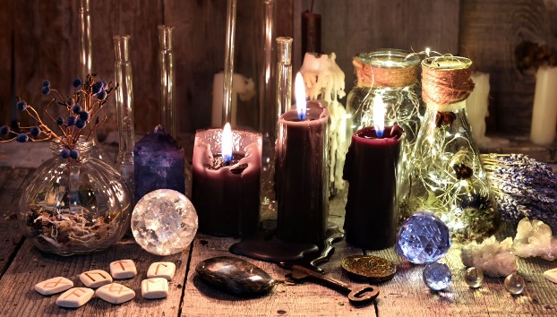 Altare esoterico con candele accese, cristalli, recipienti e rune